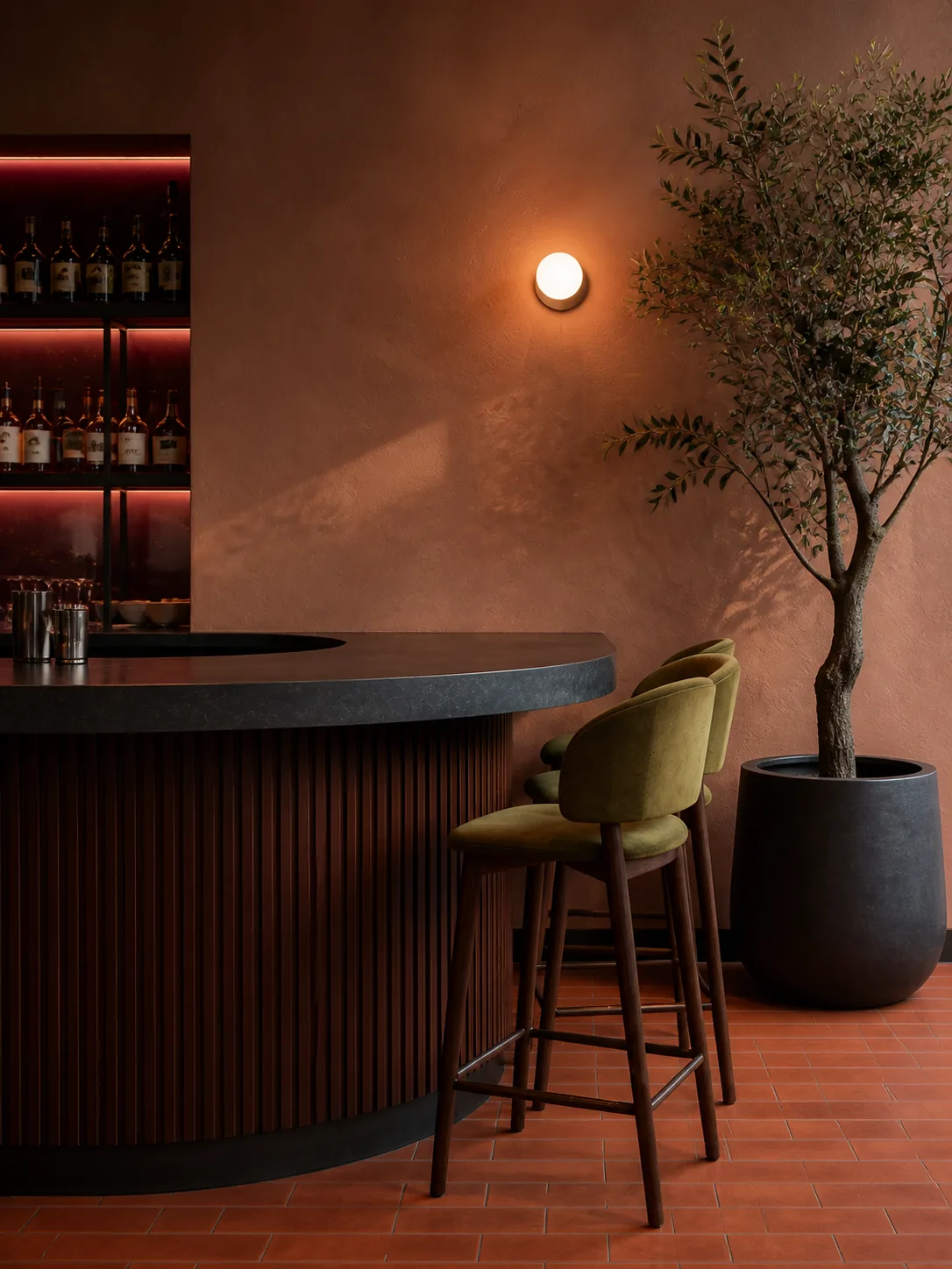 Fluted walnut, charcoal stone, olive seating and mature greenery.